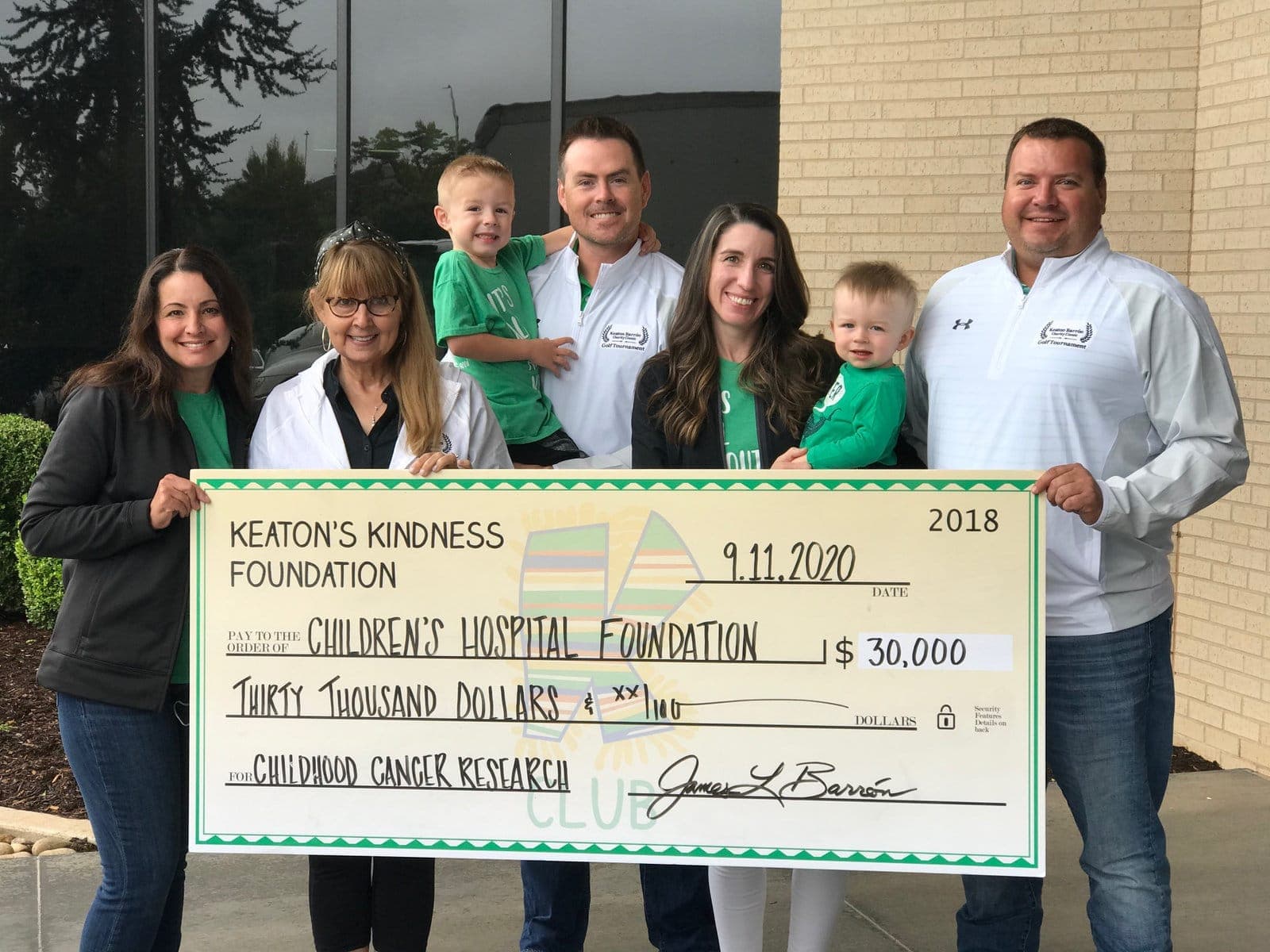 Board members and families holding a $30,000 check for the Children's Hospital Foundation